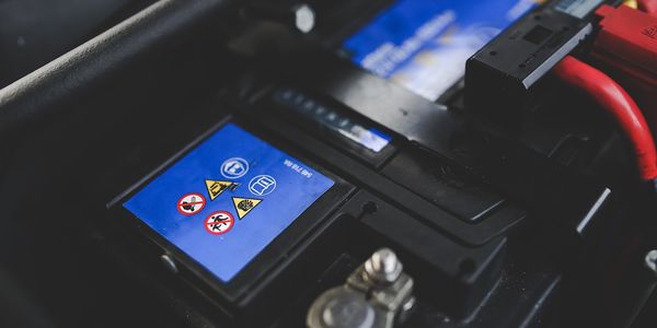 Autobatterie mit Warnsymbolen im Motorraum