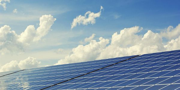 Solarmodule vor blauem Himmel mit Wolken