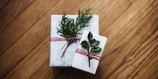 Weiß eingepacktes Geschenk mit Tannenzweig auf einem Holztisch