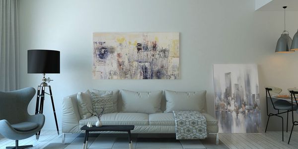 Helles Wohnzimmer mit Sofa, Stehlampe und Bildern an der Wand